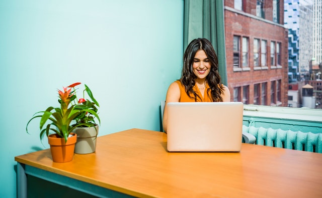 Žena sedí v kancelárii s tyrkysovými stenami a pozerá do notebooku